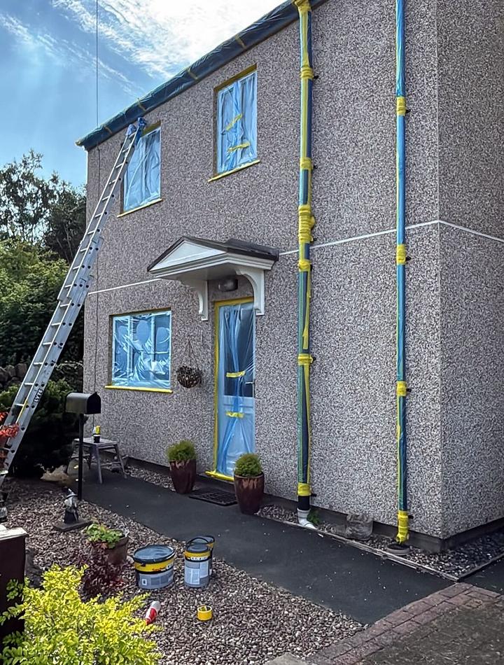 Downpipes and windows taped up on a rendered house